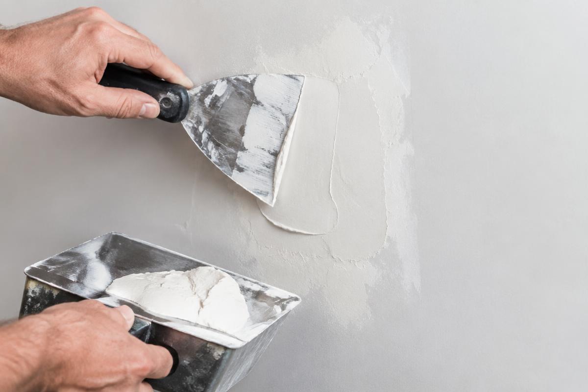Drywall repair specialist applying joint compound to a wall in Tamarac, FL